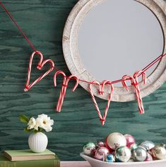 some candy canes are hanging from a string in front of a round mirror and christmas decorations