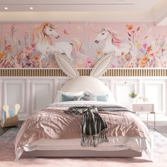 a bedroom decorated in pink and white with unicorns on the wall behind the bed