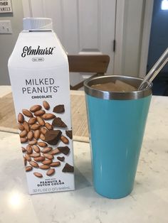 a carton of milk next to a blue cup filled with almonds