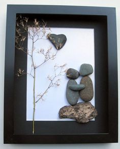 some rocks and a plant are on a white paper with black frame in front of it