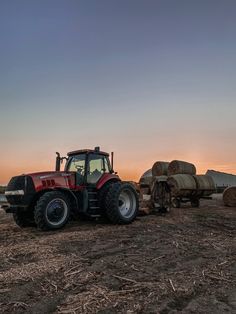 a tractor is parked in the middle of a field with hay bales behind it