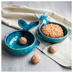 two blue bowls with nuts in them on a table