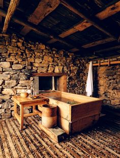 a rustic bathroom with stone walls and wood flooring