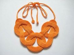 an orange necklace on a white surface with two loops attached to it and one knoted around the neck