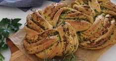 a bunch of breads sitting on top of a cutting board next to some herbs