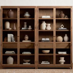 a wooden bookcase filled with lots of vases