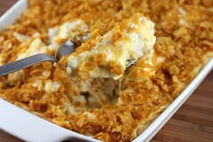 a spoonful of food is being lifted from a casserole dish with cheese