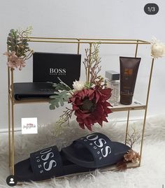 an assortment of personal items displayed on a gold shelf with white furnishing and flowers