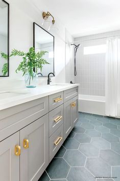 a bathroom with blue tile flooring and gold handles on the vanity, along with a large mirror over the sink