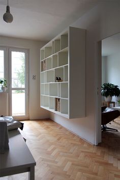 an empty room with a desk, chair and bookshelf on the wall in front of large windows