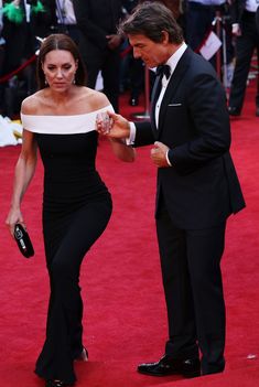 a man and woman in formal wear walking down the red carpet