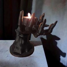 a candle that is sitting on top of a table next to a hand casting a shadow