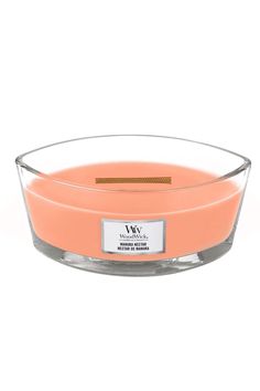 an orange candle in a glass bowl with a label on the front and back side