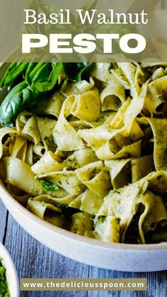 basil walnut pesto pasta in a white bowl on a wooden table with spinach