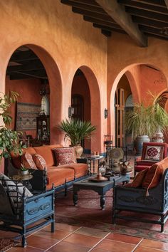 A cozy outdoor patio with arched doorways, orange walls, and vintage furniture. Spanish Inspired Restaurant, Spanish Japanese Home, Spanish Style Family Room, Spanish Colonial Revival Interior, Spanish Furniture Hacienda Style, Hispanic Interior Design, Spanish House Interior Design, Colorful Spanish Interior Design, Spanish Style Room