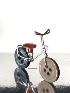 a pair of buttons attached to a metal hook on a table with water reflecting off the surface