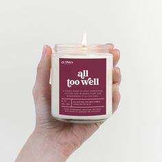 a hand holding a candle that says all too well on the front and back of it