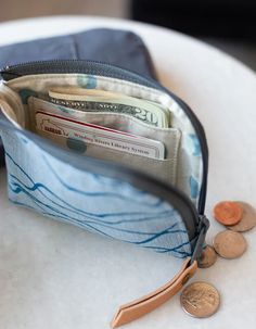 a wallet with money sticking out of it on top of a white table next to some coins