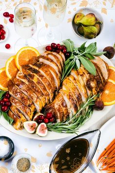 a platter with sliced turkey, oranges and cranberries