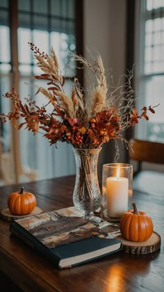 a table topped with a vase filled with lots of flowers and candles next to a book