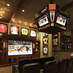 a sports themed home theater with seats and televisions on the wall behind it,