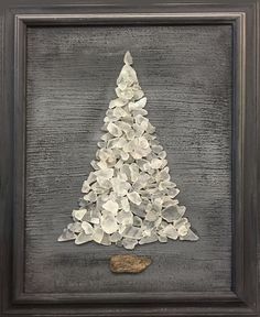 a white christmas tree made out of rocks in a black frame with a cork board underneath it