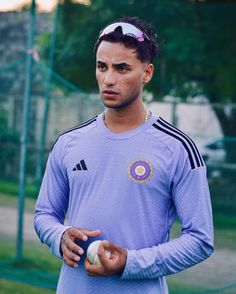 a man holding a ball in his hand while wearing a purple shirt and headband