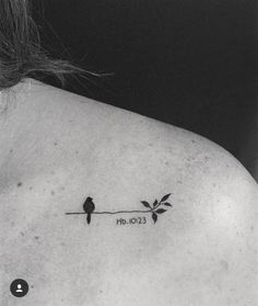 a black and white photo of a woman's back shoulder with two birds on a branch