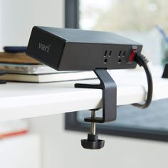 a close up of a small black device on a white table next to a window