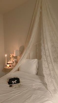 a bed with a white canopy over it and two candles on the nightstands next to it