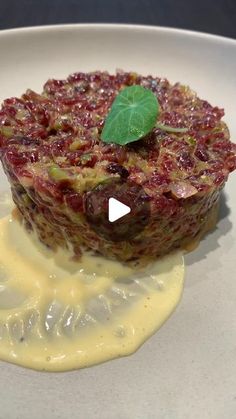 a white plate topped with food covered in sauce and garnished with a green leaf