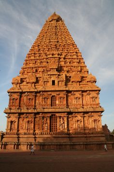 a large stone structure in the middle of a field with people standing around it and looking up