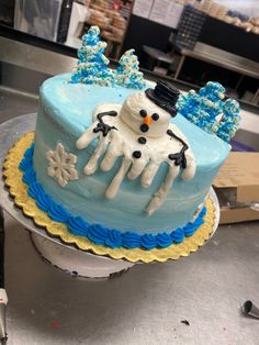 a frosted cake with an image of a snowman on top and blue icing