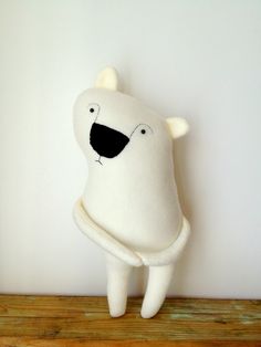 a stuffed polar bear sitting on top of a wooden table next to a white wall