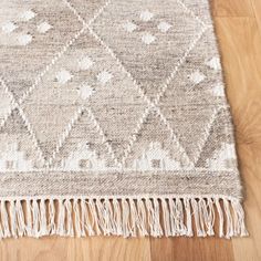 an area rug with fringes on top of it and wood flooring in the background