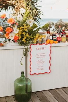 an outdoor bar with flowers and bottles on the table next to it is a sign that says salute