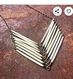 the necklace is made out of metal rods and has five smaller tubes attached to it