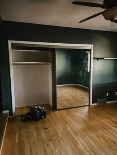 an empty room with hard wood flooring and a fan hanging from the ceiling above it