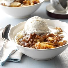 two bowls filled with food and ice cream on top of a white table cloth next to silverware