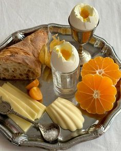 an assortment of cheeses, crackers, and bread on a silver platter