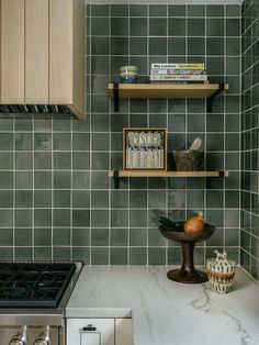 a kitchen with green tile and wooden shelves