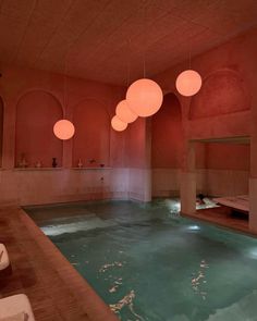 an indoor swimming pool with lights hanging from it's ceiling and water in the middle