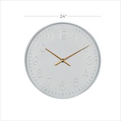 a white wall clock with gold hands and numbers on the face is shown in an angled view