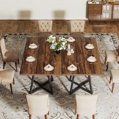 a dining room table with chairs and plates on the top, in front of an ornate rug