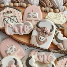 cookies decorated with farm animals and the word love are on a piece of wooden plank