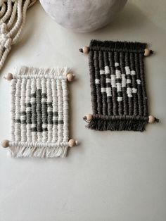 two pieces of woven art sitting on top of a table