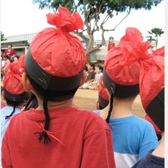 several children wearing red turbans standing in front of a group of people with their backs to the camera