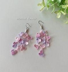 crochet flower dangle earrings in pink, purple and white on a table