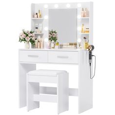 a white vanity with lights and flowers on it