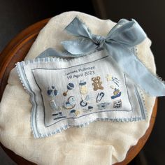 a blue ribbon is tied on top of a white cloth with embroidered pictures and words